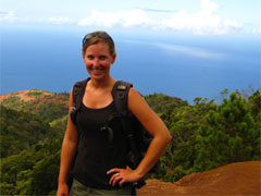 Photo of Erin, with the ocean and the top of a rainforest spread below, in the background