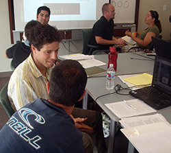 Several pairs of student and teachers in discussion and sitting around a table